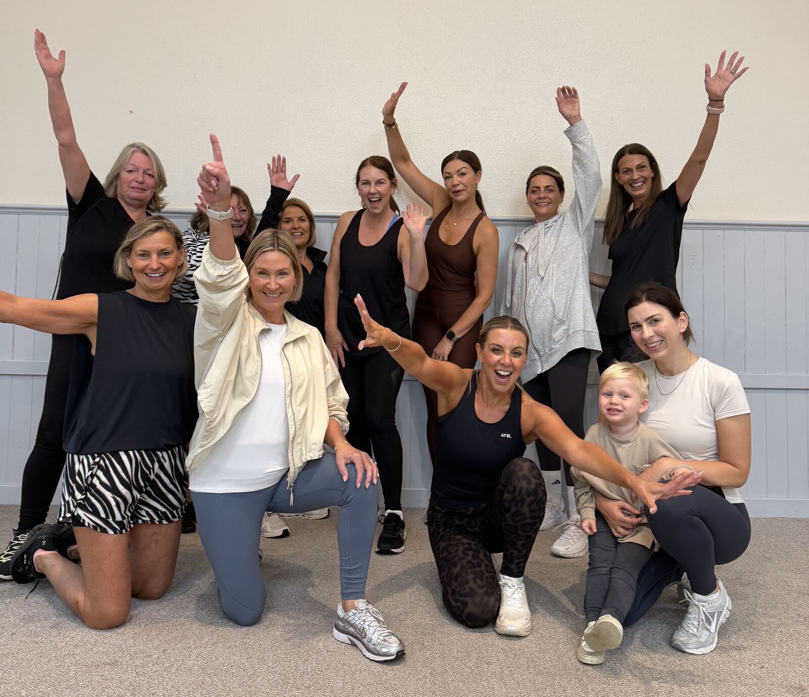 Nicola and a group of NK Body ladies cheering with their arms in the air after class